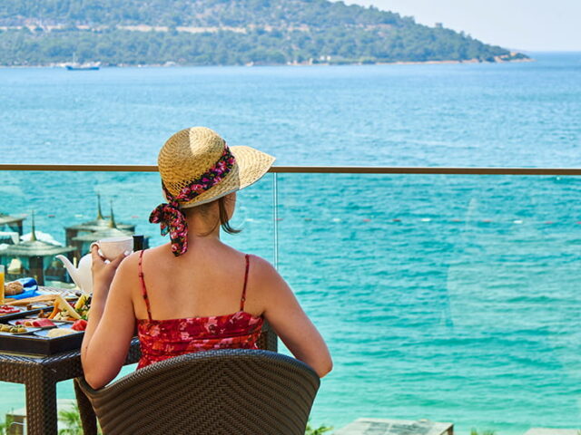 Kobieta patrząca na morze z tarasu hotelu - jak nie przytyć na urlopie