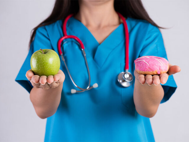 Lekarka trzymająca jabłko i pączka