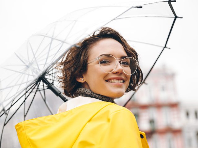 Uśmiechnięta młoda kobieta pod parasolem - już wiosną zacznij budować odporność na kolejny sezon jesienno-zimowy